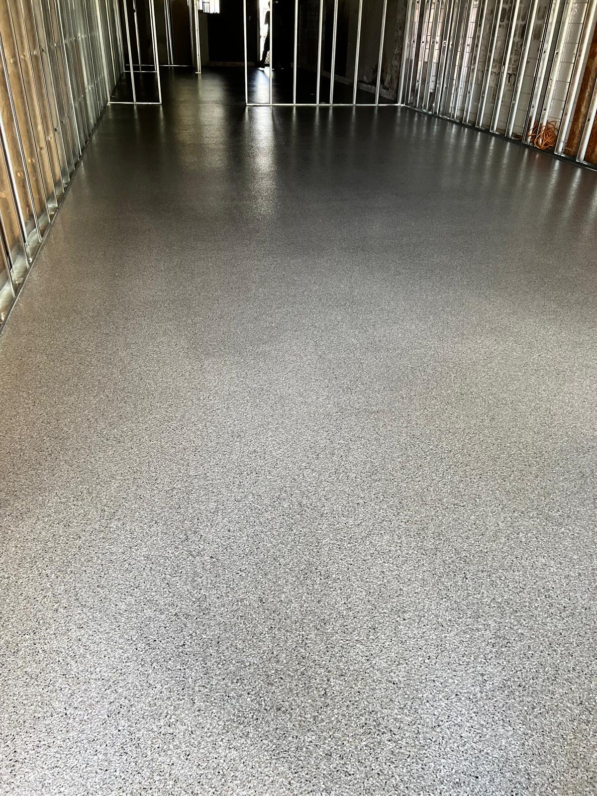 Charcoal epoxy flake floor through a fit-out lined with steel stud framing