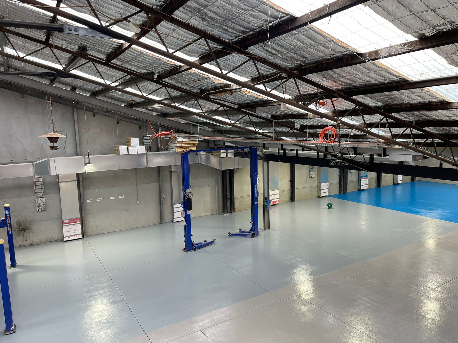 Motortuff floor with grey and blue zones marking bays in a large workshop