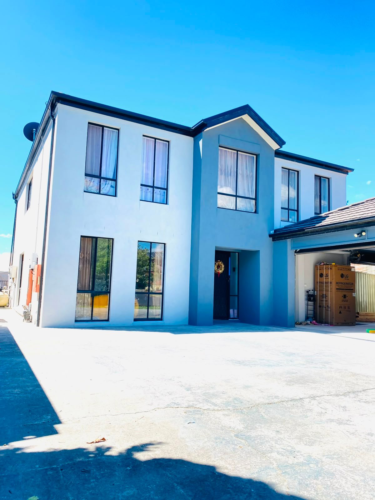 Rendered two-storey home in white and grey under a clear sky